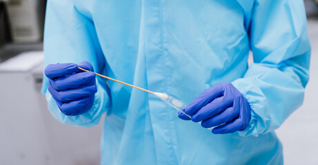 Medical scientist in PPE suit uniform holding  swab coronavirus test in laboratory