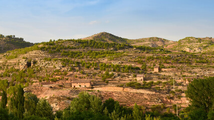 Fototapeta na wymiar Picturesque rural landscape of earthy mountains with some rocks, old haystacks, agricultural terraces called bancales and scattered trees