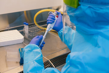 A scientist in PPE safty uniform pipetting sample experiment in biological safety cabinet (BSC).