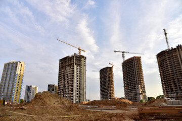 Tower cranes in action at construction site. Construction process of the new modern residential buildings. Road work and streets repair in city. Preparing to pour of concrete into formwork. Soft focus