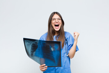 young pretty nurse shouting aggressively with an angry expression or with fists clenched...