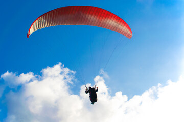 Paraglider in the blue sky with white clouds