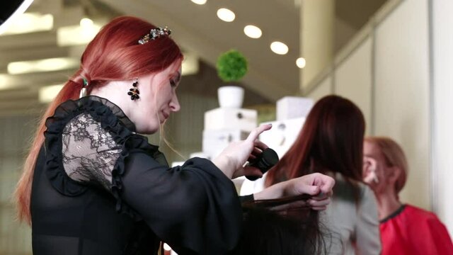 Woman hairdresser with red hair color sprinkle powder on hair roots to add volume. Video