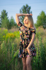 Naklejka na ściany i meble overlight bright portrait of a charming attractive blonde in flowery dress in the field. 