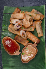 Egg rolls on banana leaf served with chili and peanut sauce