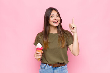 young pretty woman with an ice cream feeling like a happy and excited genius after realizing an...