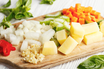 Fresh raw chopped vegetables for cooking soup on wooden board