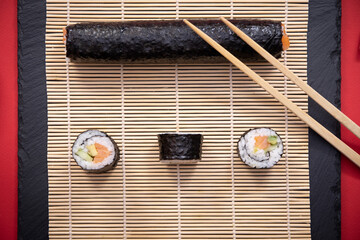 Présentation de plat de cuisine Japonaise, sushi et maki sur fond noir avec sauce soja et baguettes.	
