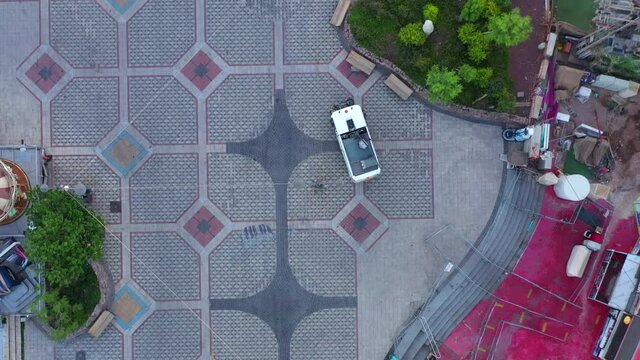Street sweeper Brush Car cleaning a coastline resort promenade at sunrise, Aerial view.