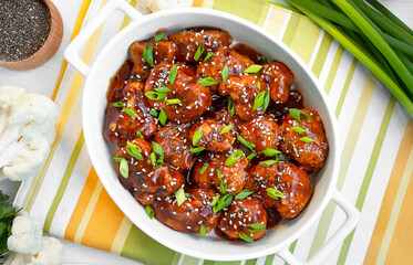 Fried cauliflower in sauce and sesame seeds. Asian cuisine. White wooden background. Copy space.