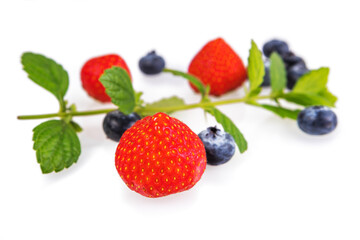 Strawberries and blueberries with mint leaves on a white background