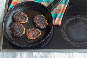 electric stove. Induction. There is a frying pan with food on it. The food is burnt.