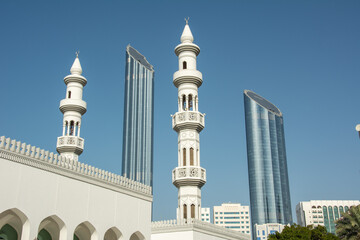 Fototapeta na wymiar The view of modern skyscraper towers and white washed minarets of an old church in Abu Dhabi, United Arab Emirates
