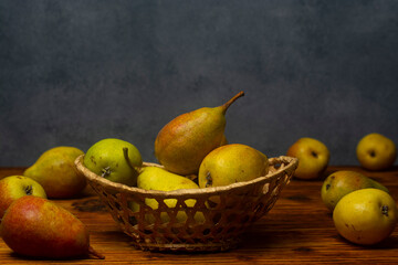 Fresh pears in a basket on a wooden table. Free space for an inscription.