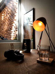 Speaker, headphones and music on a wooden desks with a glass of water and a lamp. Lifestyle, relaxation.