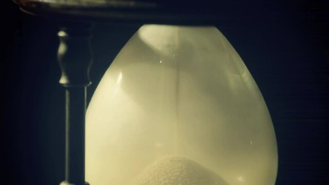 Fine sand falling into the bottom half of a magnificent hourglass (an ancient device for the measurement of time). Shot in real time.
