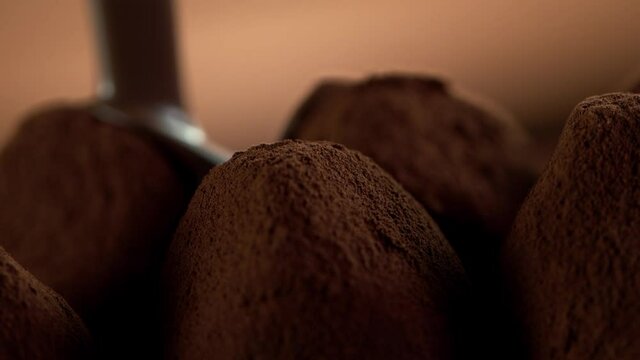 Super slow motion of pouring dark hot chocolate on praline bonbon. Filmed with cinema high speed camera