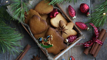Christmas theme: gingerbread cookies in a box, Christmas decorations, spices, pine branches on a dark wooden background                      