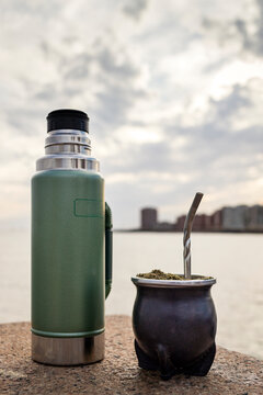 Vertical close-up of a mate and thermos. The infusion made with yerba mate is considered in Uruguay as the national drink. In the background the R&iacute;o de la Plata river and the city of Montevideo