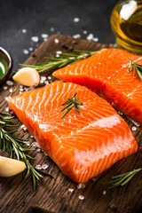 Salmon fish with ingredients at black table.