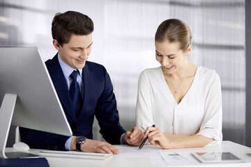 Fototapeta premium Business people discussing something while sitting in office. Focus at businesswoman while talking to her male colleague. Teamwork and meeting concept