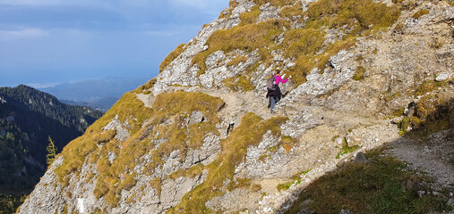 Wanderer hangelt sich an Kette an Steilwand entlang
