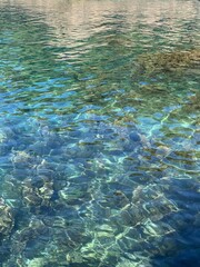 Fototapeta na wymiar Turquoise crystal clear calm rippled Adriatic sea water surface, pebble seabed with seaweed algae, relax, meditation, tranquility in summer season.