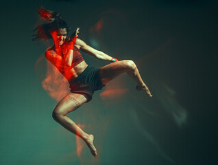 A young female fighter performs a jump kick. Long exposure shot