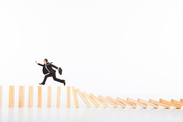 businessman running and catching  on toppling dominoes 