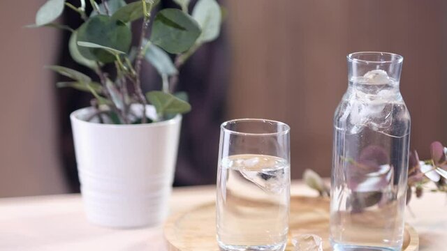 Pouring carbonate mineral water into a glass with ice cubes. Slow motion.