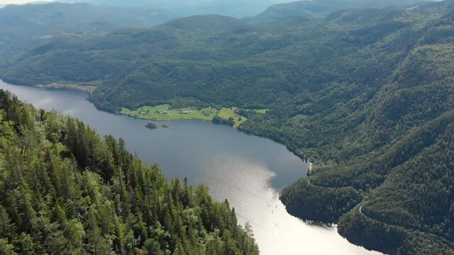 Beautiful Norwegian highlands, lake beneath mountainside forest, aerial reveal