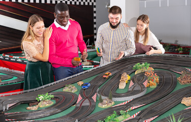 Happy two couples enthusiastically remotely control car models on race track