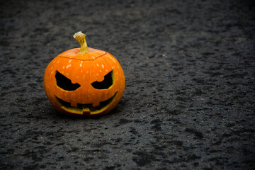 
There is a scary Halloween pumpkin against a dark background. The background is blurred.