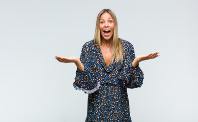 young pretty woman feeling happy, excited, surprised or shocked, smiling and astonished at...