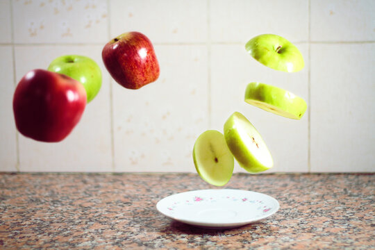 Sliced Green Apple Levitating Over A Small Plate On Marble Table And Apples Levitating