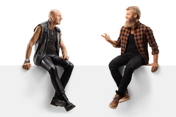 Punk and a bearded casual guy sitting on a blank panel and talking