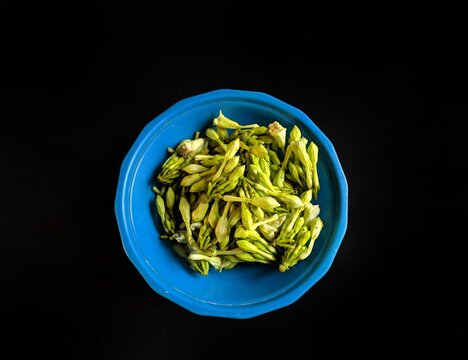 Fernaldia pandurata loroco flower on a plate on black background, typical food of Guatemala