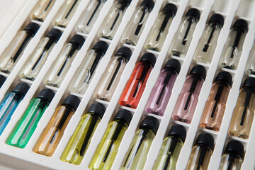 Sample of colored perfume bottles with different types of fragrances and aromas in a makeup case on the table. Beauty concept. Feminine concept. Colorful concept.