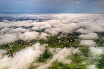 Aerial view of white clouds above a town or village with rows of