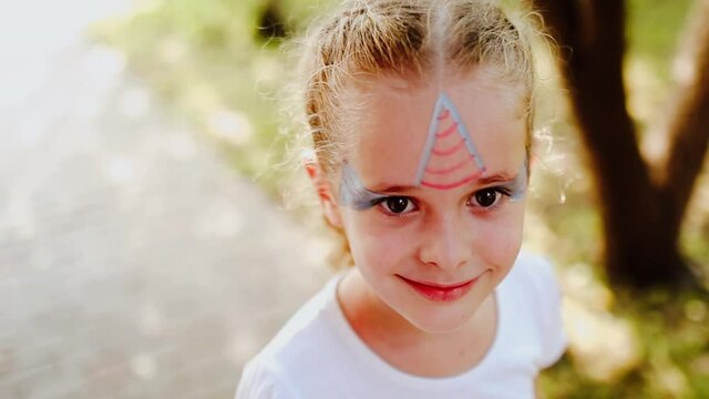 Portrait of young pretty girl with face painting like unicorn at her face. Copy space. Slow motion video.