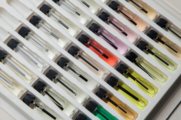 Sample of colored perfume bottles with different types of fragrances and aromas in a makeup case on the table. Beauty concept. Feminine concept. Colorful concept.
