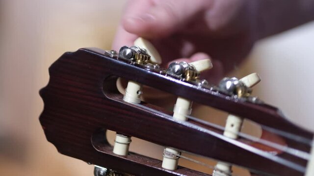tuning an acoustic guitar by hand. close up