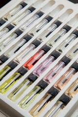 Sample of colored perfume bottles with different types of fragrances and aromas in a makeup case on the table. Beauty concept. Feminine concept. Colorful concept.