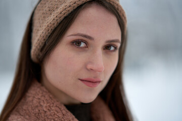 Portrait of a beautiful woman in beige coat in winter forest.