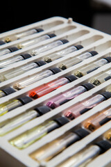 Naklejka premium Sample of colored perfume bottles with different types of fragrances and aromas in a makeup case on the table. Beauty concept. Feminine concept. Colorful concept.