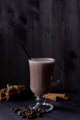 cup of cappuccino.hot drinks winter and autumn. glass of hot chocolate with whipped cream, coffee beans and cinnamon sticks on a dark background. hot drinks on a wooden background. vertical.copy space