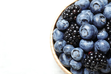 Blueberries and blackberries in bowl on white background, closeup