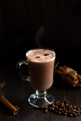 hot drinks. cup of hot chocolate. glass of hot cocoa with whipped cream, coffee beans and cinnamon sticks on a dark background. hot drinks on a wooden background. winter and autumn.vertical.copy space