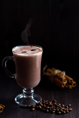 cup of coffee. glass of hot chocolate with whipped cream, coffee beans and cinnamon sticks on a dark background. hot drinks on a wooden background. winter and autumn. vertical. copy space