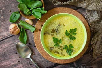 Spinach soup with cream on a rustic wooden table. Top view flat lay background.
